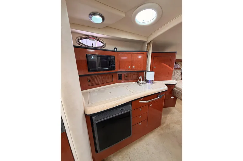 Slide: The Image of 2005 Sea Ray 300 Sundancer interior kitchen with microwave, sink, and storage cabinets. - 28