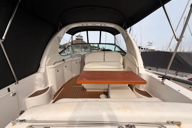 Slide: The Image of 2005 Sea Ray 300 Sundancer interior with wooden table and seating, docked at marina. - 9