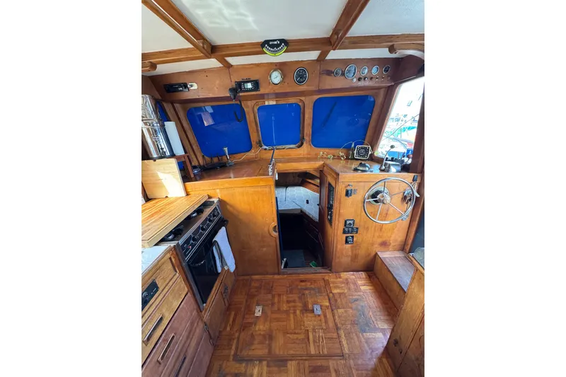 Slide: The Image of 1978 CHB 35 boat interior with wooden helm, kitchen, and blue window covers. - 17