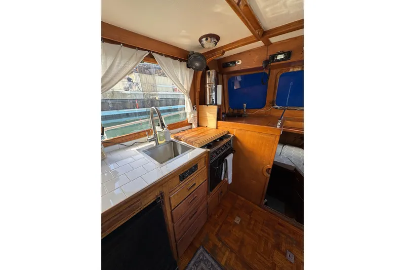 Slide: The Image of 1978 CHB 35 boat interior with wooden cabinetry, sink, and stove in the galley area. - 19