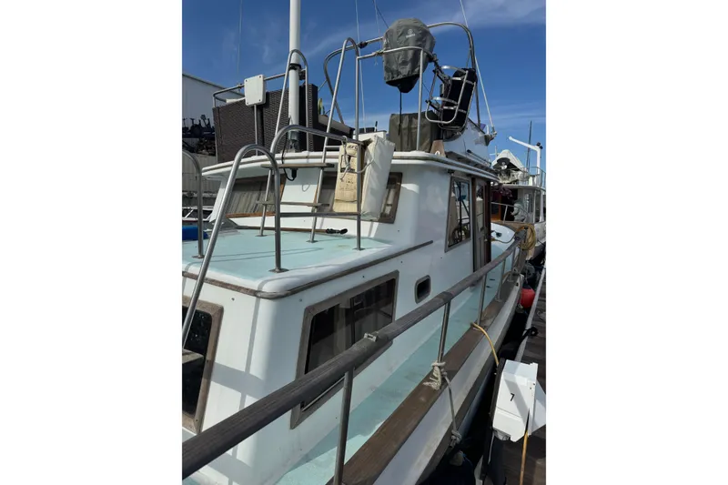 Slide: The Image of 1978 CHB 35 boat docked, featuring upper deck and railing under clear blue sky. - 2