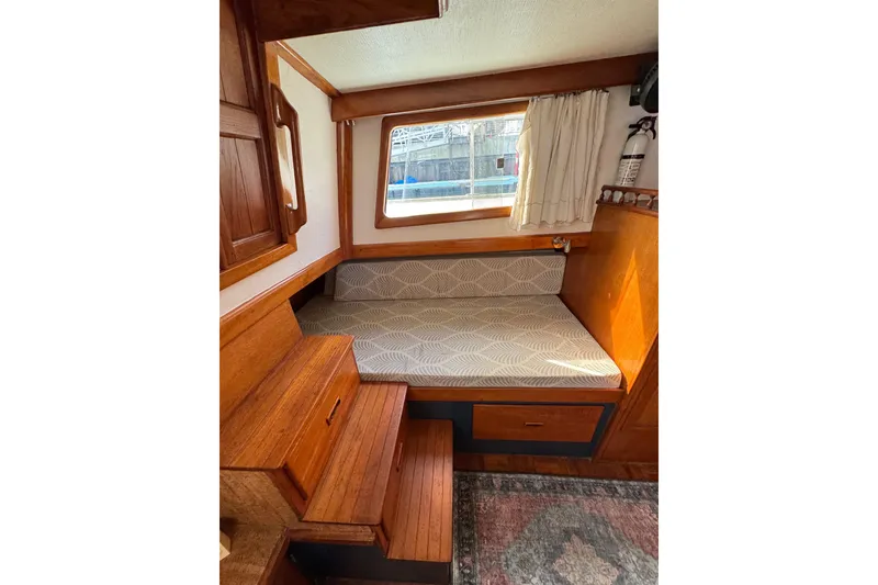 Slide: The Image of Cozy cabin interior of a 1978 CHB 35 boat with wooden accents and patterned bedding. - 35