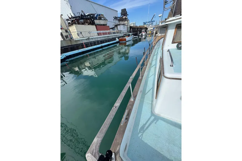 Slide: The Image of 1978 CHB 35 boat docked in a calm marina with industrial backdrop. - 8