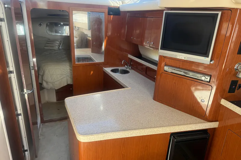 Slide: The Image of 2005 Regal Commodore 3880 yacht interior with kitchen, TV, and cozy bedroom. - 10