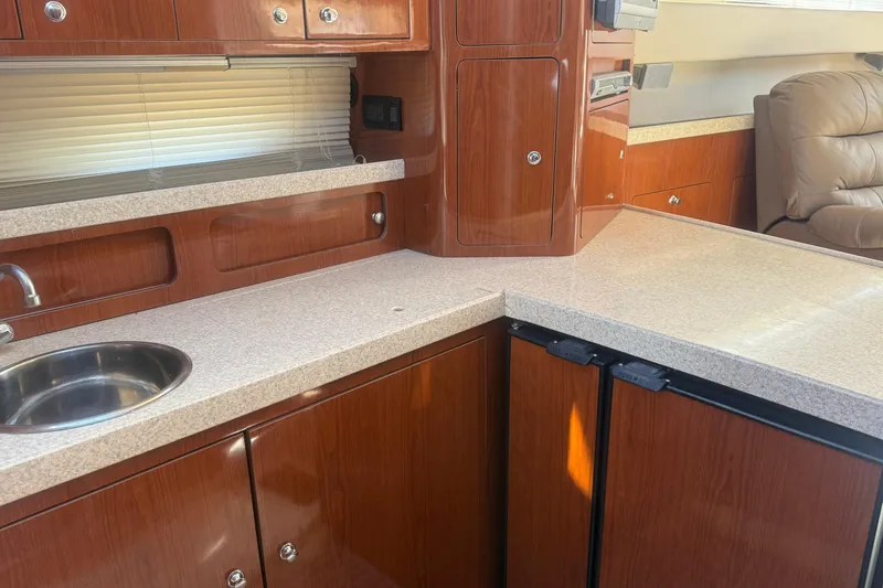 Slide: The Image of 2005 Regal Commodore 3880 yacht kitchen with wood cabinetry and compact appliances. - 11
