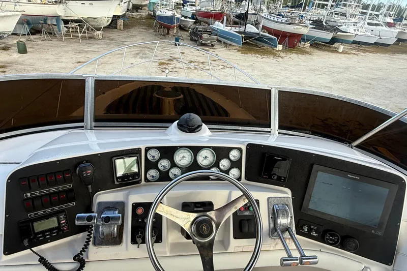 Slide: The Image of 2005 Regal Commodore 3880 helm with gauges, controls, and navigation equipment in a boatyard setting. - 24