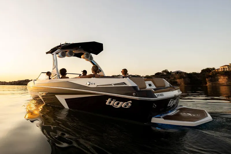 Slide: The Image of Manufacturer Provided Image: 2023 Tigé 24RZX boat cruising on a lake at sunset with passengers. - 12