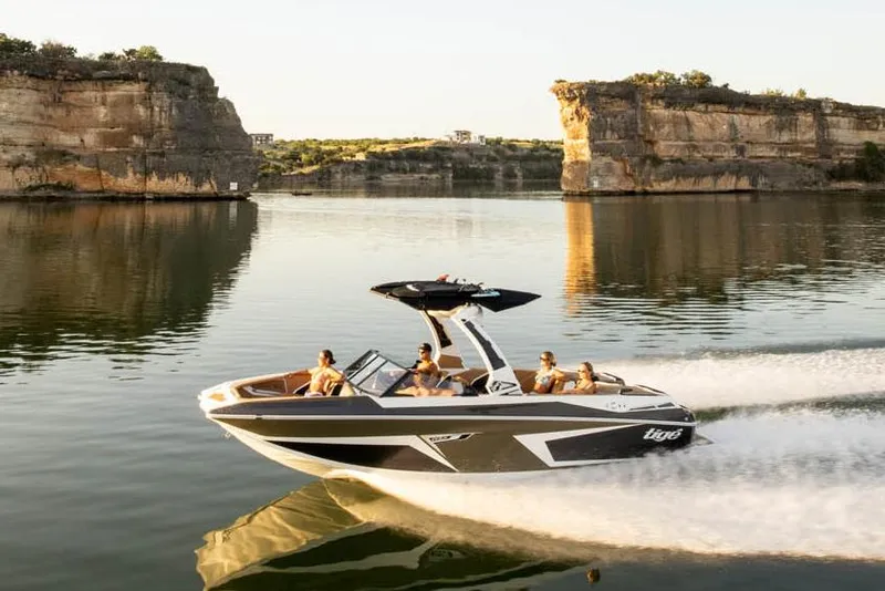 Slide: The Image of Manufacturer Provided Image: 2023 Tigé 24RZX boat cruising on a serene lake with rocky cliffs in the background. - 13
