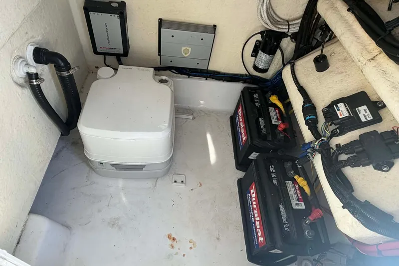 Slide: The Image of 2016 Crevalle 26 Bay boat interior with batteries and portable toilet setup. - 17