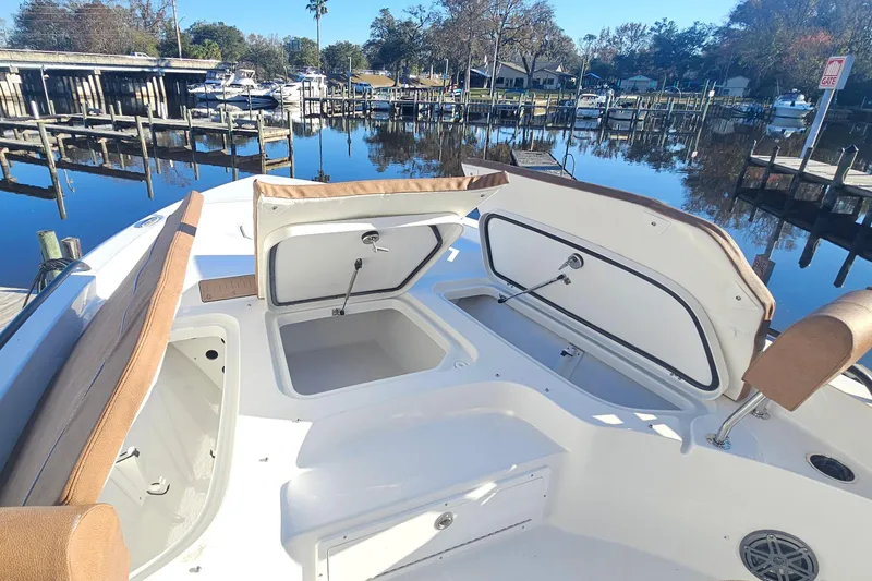 Slide: The Image of 2026 Sea Hunt BX 25 FS boat interior with open storage compartments at a marina. - 24