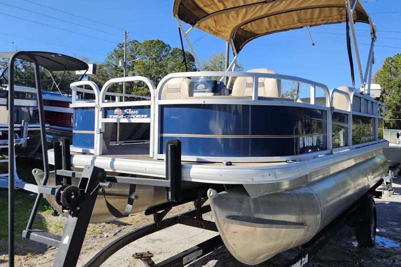 Slide: The Image of 2023 Sun Tracker Bass Buggy 18 DLX pontoon boat on trailer, blue and beige design. - 3