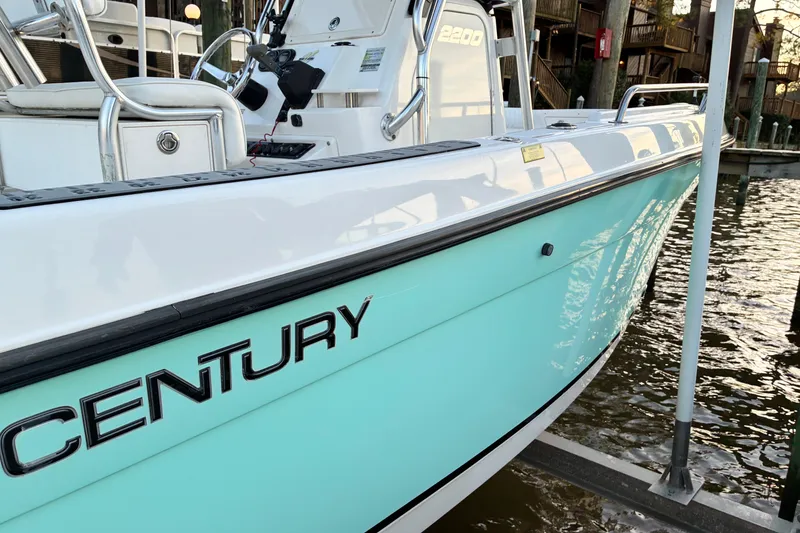 Slide: The Image of 2004 Century 2200 Center Console boat docked, featuring sleek design and turquoise hull. - 37
