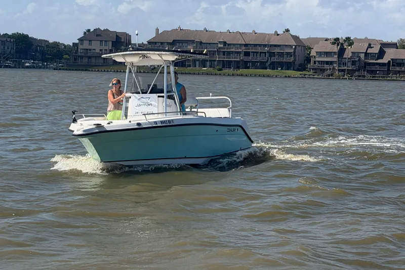 Slide: The Image of 2004 Century 2200 Center Console boat cruising on a lake near waterfront homes. - 45