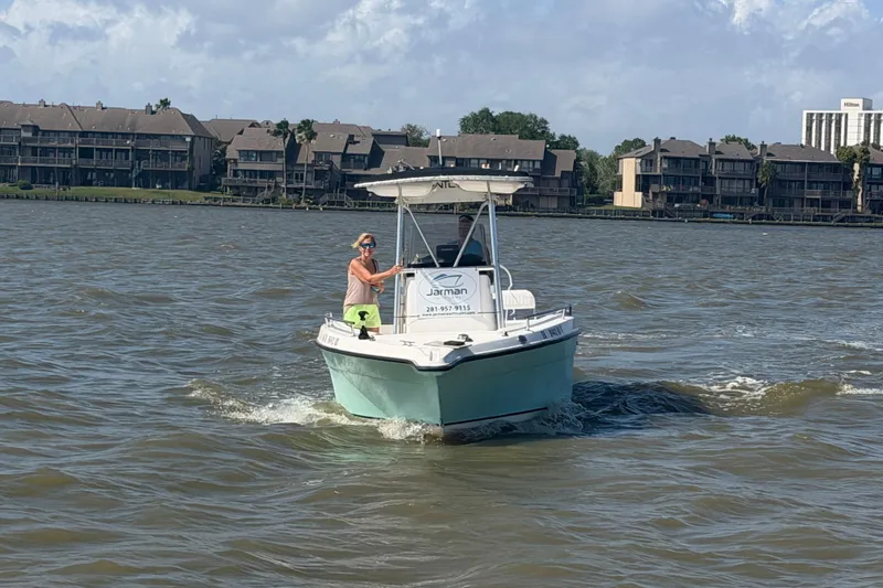 Slide: The Image of 2004 Century 2200 Center Console boat cruising on a lake near waterfront homes. - 46