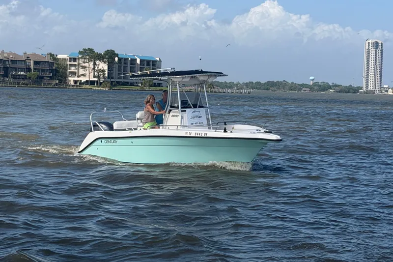 Slide: The Image of 2004 Century 2200 Center Console boat cruising on a sunny day near coastal buildings. - 47