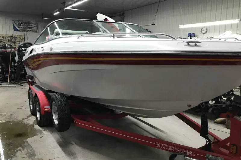 Slide: The Image of 2001 Four Winns 210 Horizon boat on red trailer in garage setting. - 5