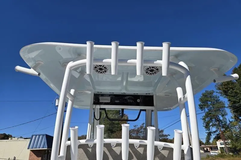 Slide: The Image of 2026 Sea Hunt Ultra 285 Coffin Box boat with rod holders and speakers under a clear blue sky. - 14