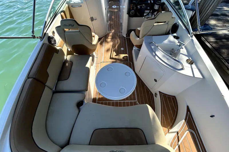 Slide: The Image of 2007 Sea Ray 260 Sundeck interior with seating, table, and helm, docked by water. - 11