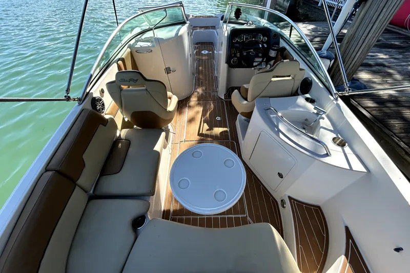 Slide: The Image of 2007 Sea Ray 260 Sundeck interior with seating, table, and helm, docked by water. - 12