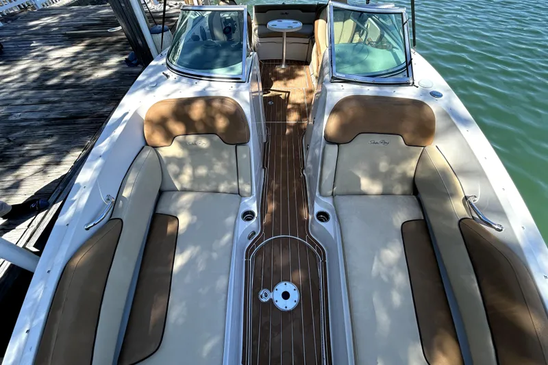 Slide: The Image of 2007 Sea Ray 260 Sundeck interior with tan seating and wooden deck, docked by water. - 21