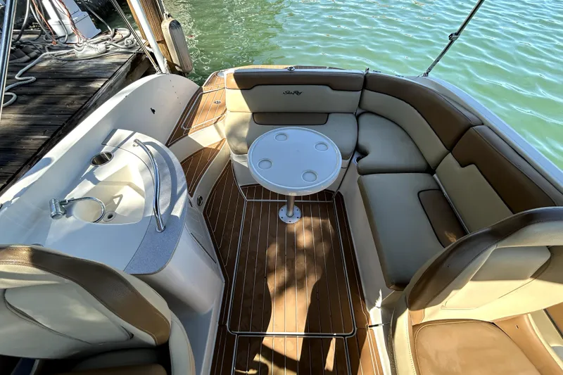 Slide: The Image of 2007 Sea Ray 260 Sundeck interior with seating and table, docked by the water. - 24