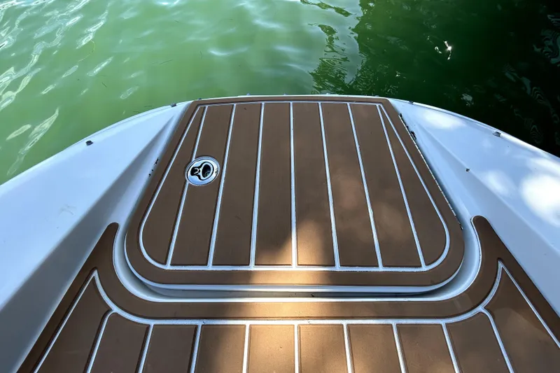 Slide: The Image of 2007 Sea Ray 260 Sundeck swim platform with teak-style decking, near green water. - 82