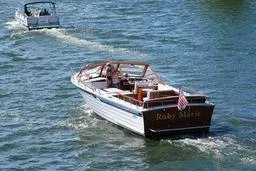 The Image of 1987 Skiff Craft 31' Runabout cruising on a sunny day with an American flag. - 1