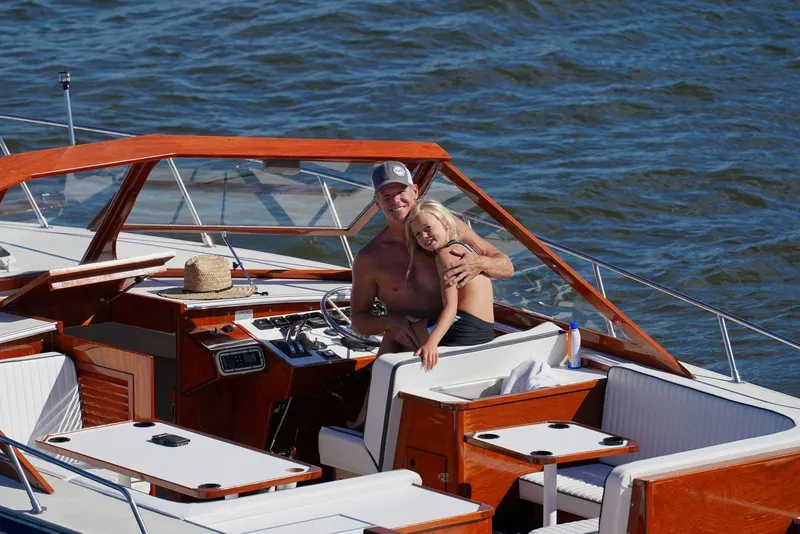 Slide: The Image of 1987 Skiff Craft 31' Runabout on water with two people enjoying a sunny day. - 10