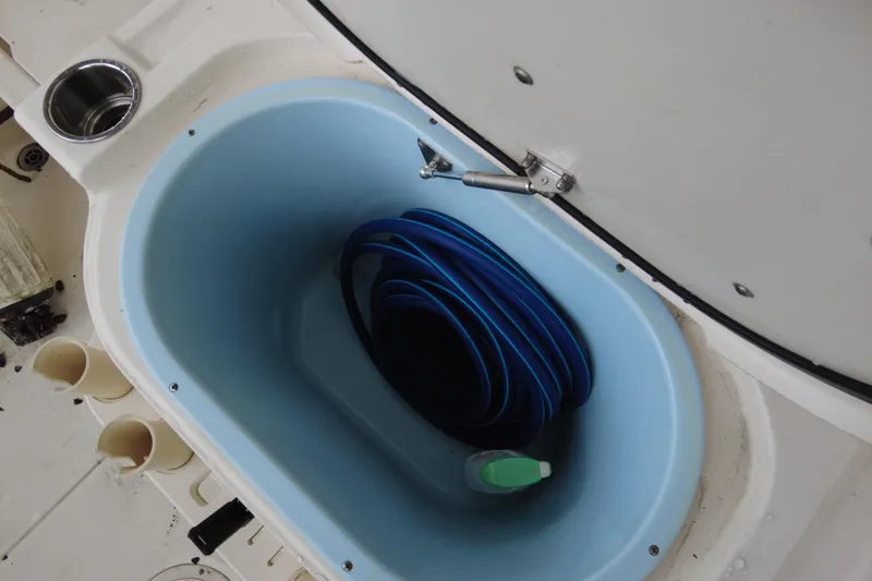 Slide: The Image of 2016 Grady-White Seafarer 228 boat storage compartment with coiled blue hose. - 9