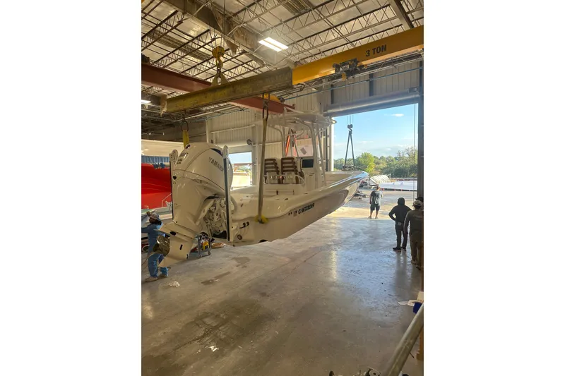 The Image of 2026 Contender 26 Bay boat in warehouse, suspended by crane, with Yamaha engine. - 0