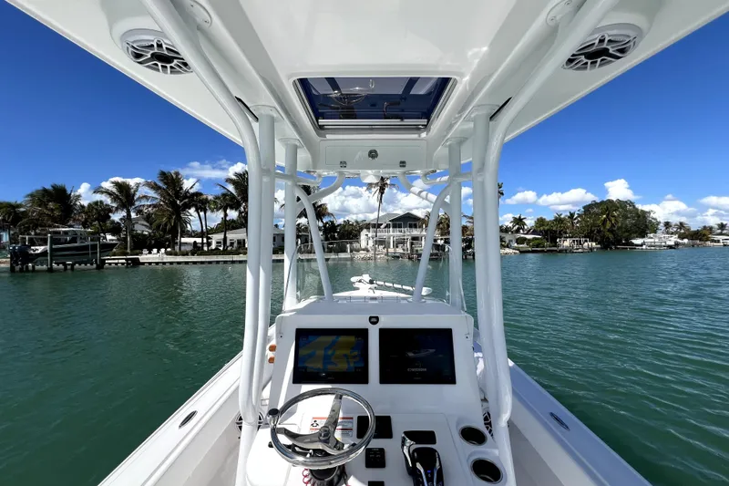 Slide: The Image of 2026 Contender 26 Bay boat on calm water, featuring modern dashboard and tropical backdrop. - 21
