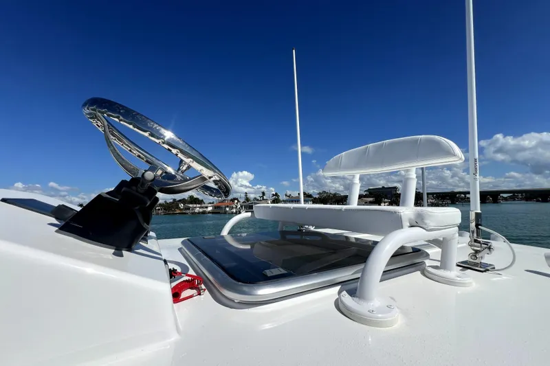 Slide: The Image of 2026 Contender 26 Bay boat helm with steering wheel and seating, under clear blue sky. - 28
