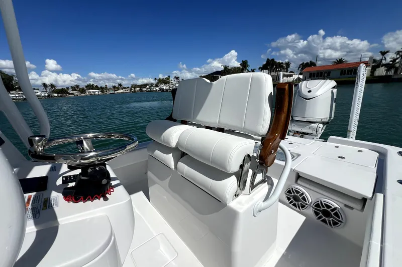 Slide: The Image of 2026 Contender 26 Bay boat interior with white seating and steering wheel, on a sunny day. - 30