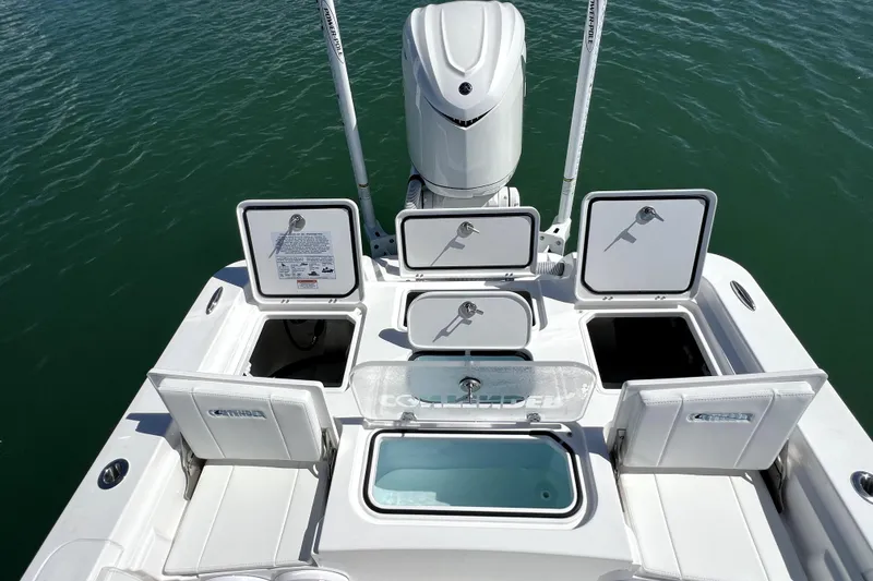Slide: The Image of 2026 Contender 26 Bay boat with open storage compartments and motor, on water. - 39