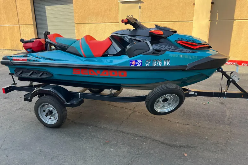 The Image of 2018 Sea-Doo Wake Pro 230 on trailer, teal and red design, parked outdoors. - 1