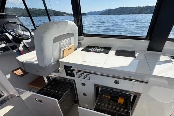 Slide: The Image of 2021 Regal 36 Grande Coupe interior with helm, kitchen, and scenic lake view. - 3