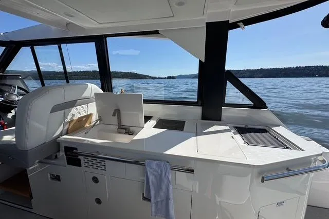 Slide: The Image of 2021 Regal 36 Grande Coupe yacht interior with kitchenette, overlooking serene waters. - 4
