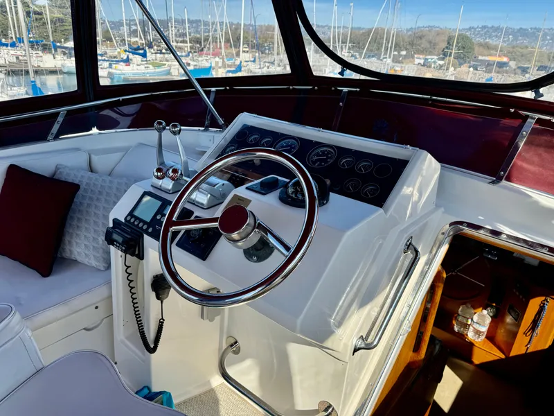 Slide: The Image of 1997 McKinna 48 Pilothouse helm with steering wheel and control panel, docked at marina. - 11