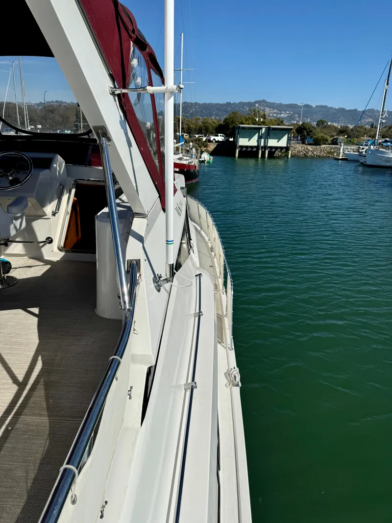 Slide: The Image of 1997 McKinna 48 Pilothouse yacht docked in a serene marina setting. - 13