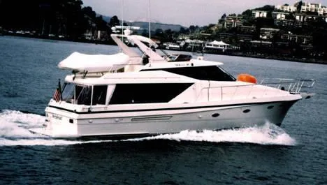 Slide: The Image of 1997 McKinna 48 Pilothouse yacht cruising on water near coastal homes. - 2