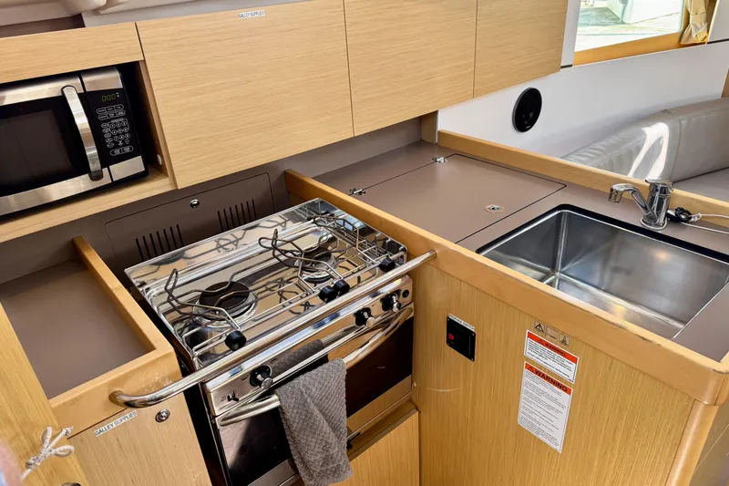 Slide: The Image of Compact kitchen in 2018 Beneteau Oceanis 35.1 yacht with stove, sink, and microwave. - 16