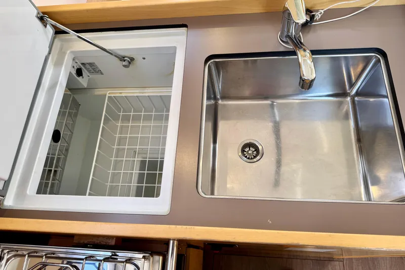 Slide: The Image of Kitchen sink and open fridge on 2018 Beneteau Oceanis 35.1 yacht. - 31