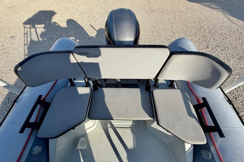 Slide: The Image of 2019 Zodiac Open 5.5 boat seating area with gray cushions and red accents. - 13