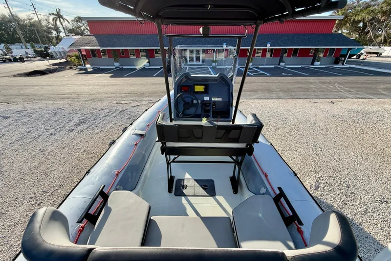Slide: The Image of 2019 Zodiac Open 5.5 boat interior with console, parked near a red building. - 15