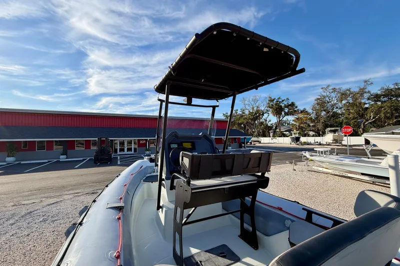 Slide: The Image of 2019 Zodiac Open 5.5 boat with canopy, parked near a red building under a blue sky. - 16