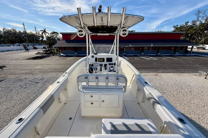 Slide: The Image of 2021 Cobia 237 Center Console boat with T-top, parked in a lot under blue sky. - 20