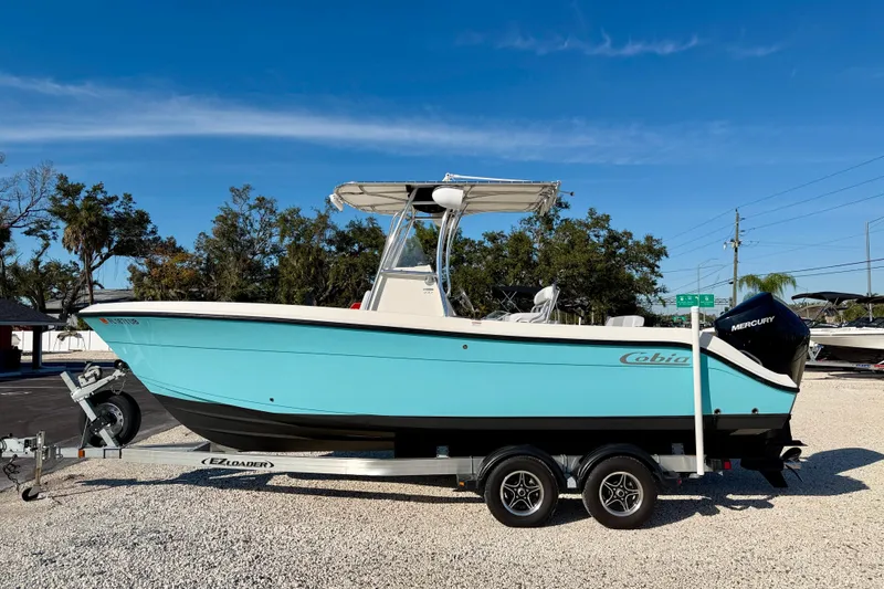 Slide: The Image of 2021 Cobia 237 Center Console boat on trailer, blue hull, parked outdoors. - 5