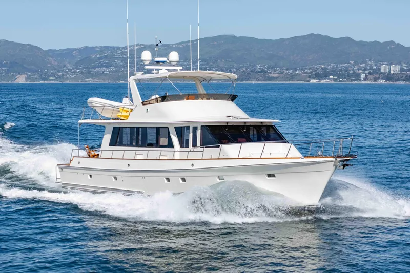 Slide: The Image of 2000 Offshore Yachts Flushdeck cruising on open water with scenic mountain backdrop. - 2