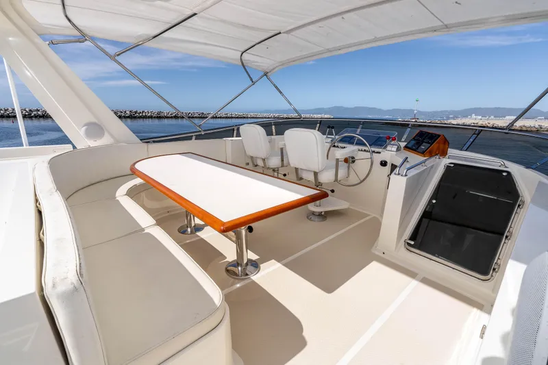 Slide: The Image of 2000 Offshore Yachts Flushdeck with spacious seating and helm, docked in a serene marina. - 21