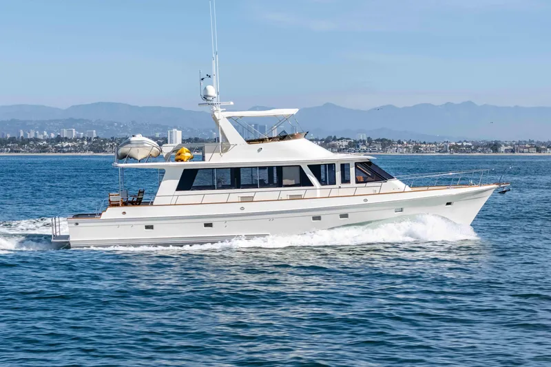 Slide: The Image of 2000 Offshore Yachts Flushdeck cruising on open water with cityscape in background. - 45